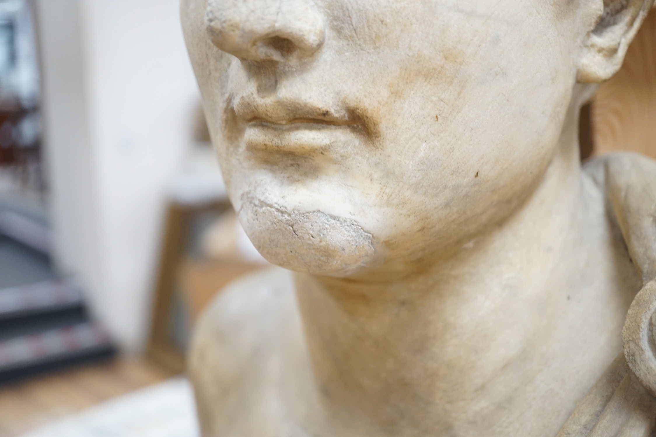 After the Antique marble bust of a Roman man wearing a Chlamys with a buckle at the shoulder, later socle and repairs, 54cm tall